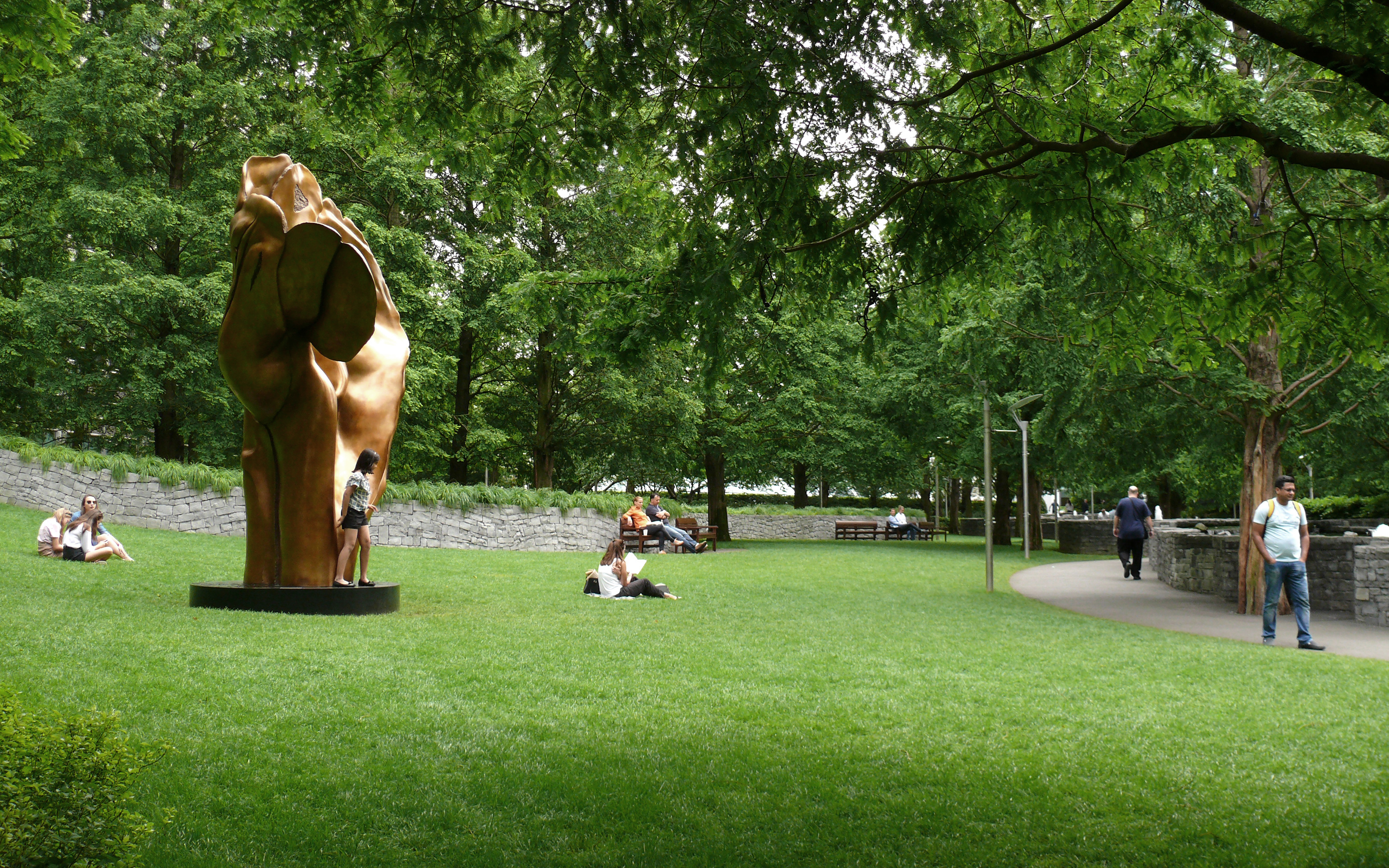 The park also hosts outdoor exhibitions and events. Bronze sculpture on the lawn and people relaxing in the park